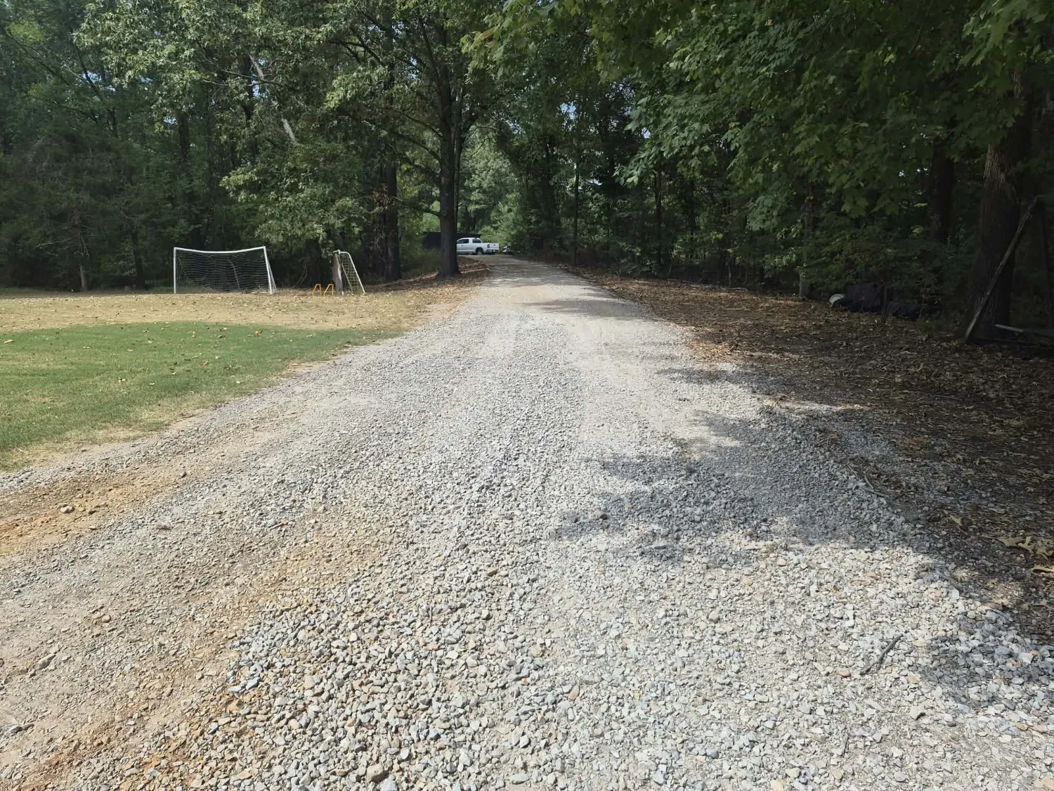Long gravel driveway with a level, even surface after land plane resurfacing